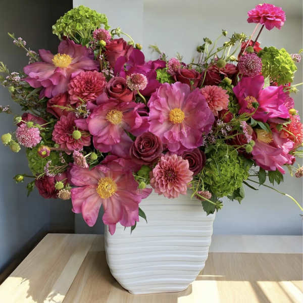Pink and magenta flowers arranged in a white vase