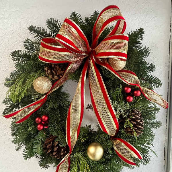 Christmas wreath with red and gold ribbon, pinecones, and ornaments