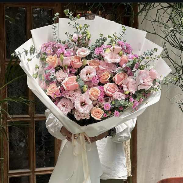 Large bouquet of pink roses and lisianthus wrapped in white paper