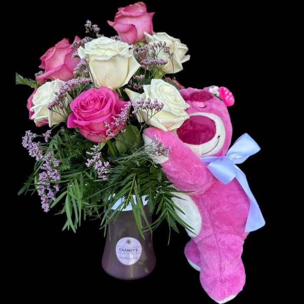 Pink and white roses in a vase with a pink teddy bear and ribbon