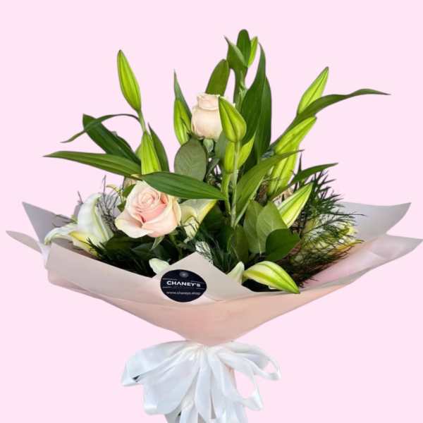 Bouquet of pale pink roses and white lilies wrapped in blush paper