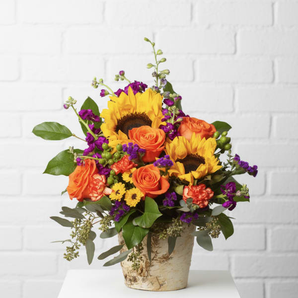 Bouquet of sunflowers and orange roses in a rustic vase