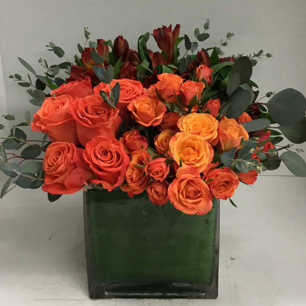 Orange and yellow roses arranged in a green vase