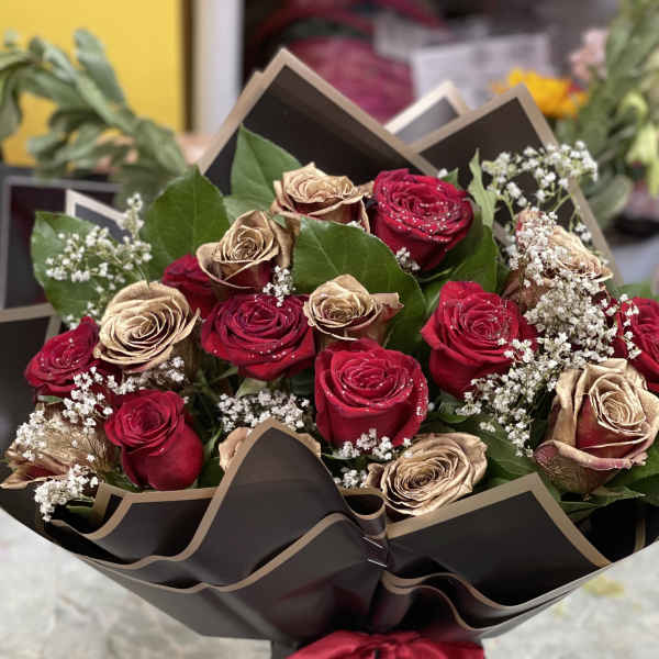 Bouquet of red and gold roses wrapped in black paper with a red ribbon