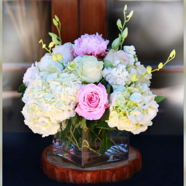 Pink and white floral arrangement in a square glass vase