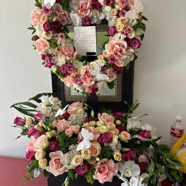 Heart-shaped floral tribute with pink and white roses on a stand