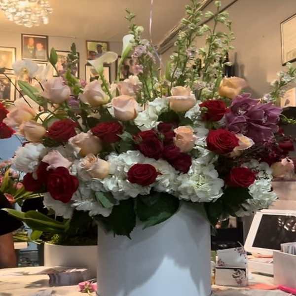 Large mixed flower arrangement in a white hat box with red and blush roses