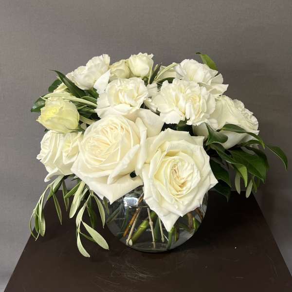 White roses and carnations arranged in a glass bowl vase