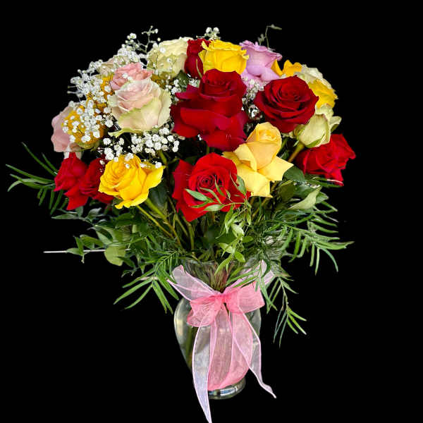 Bouquet of multicolored roses in a glass vase with a pink ribbon
