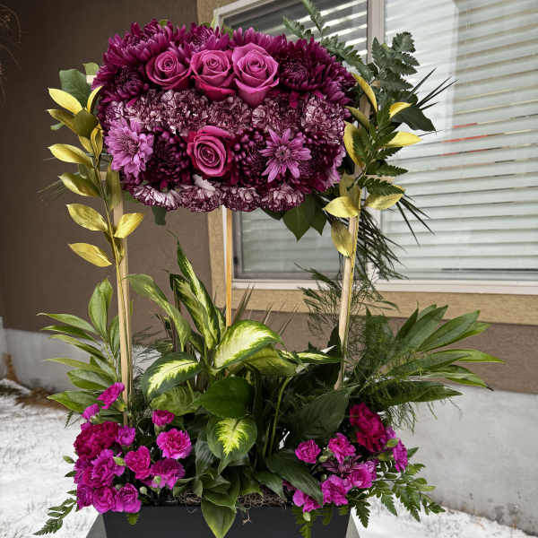Tall magenta floral arrangement in a black planter with mixed greenery