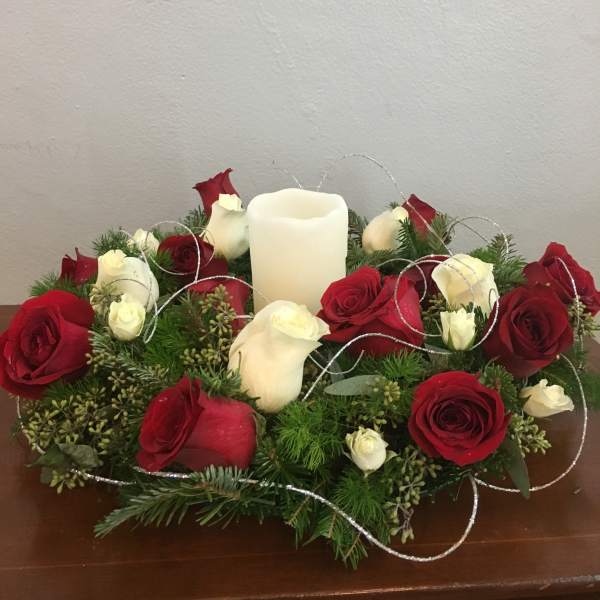 Red and white roses arranged around a white pillar candle