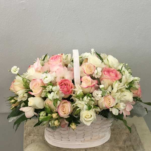 Basket of pink and white roses with small white flowers