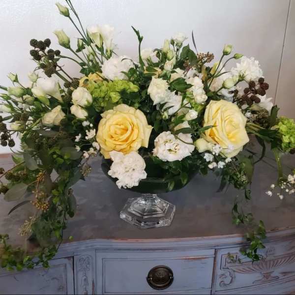 Cream and white floral arrangement in a clear pedestal vase