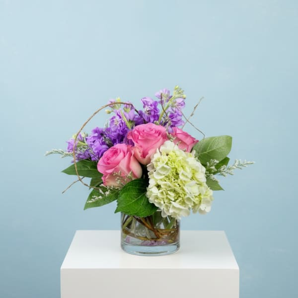 Pink roses and purple flowers in a glass vase
