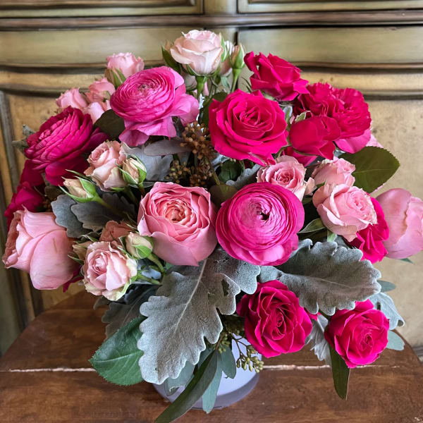 Pink and hot pink roses with ranunculus in a white vase