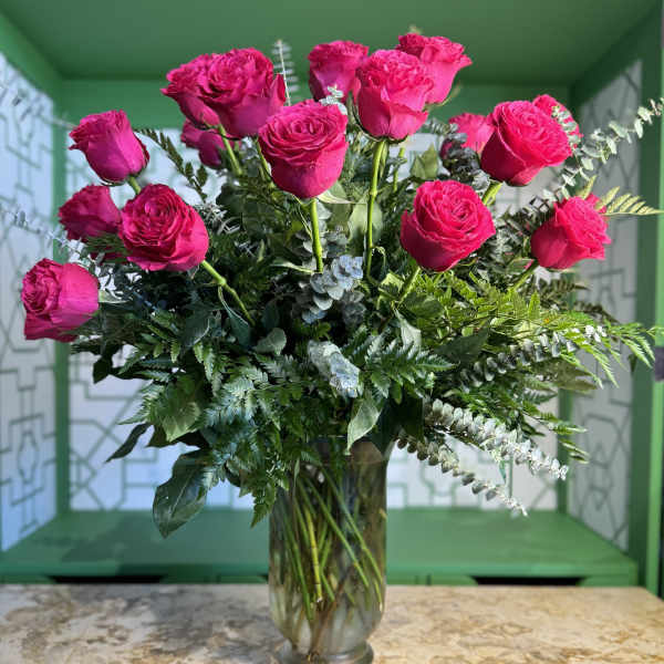 Pink roses arranged in a clear glass vase with mixed greenery