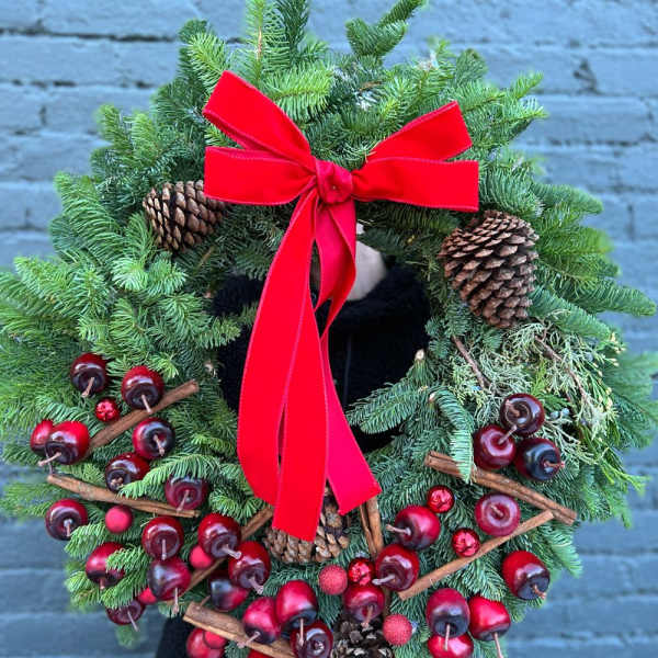 Evergreen wreath with red ribbon, pinecones, and red berry accents