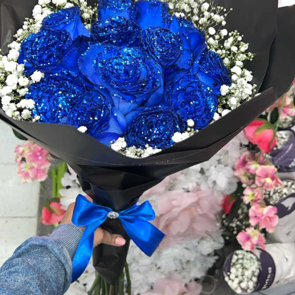 Bouquet of blue roses with white baby's breath in black wrap and a blue ribbon