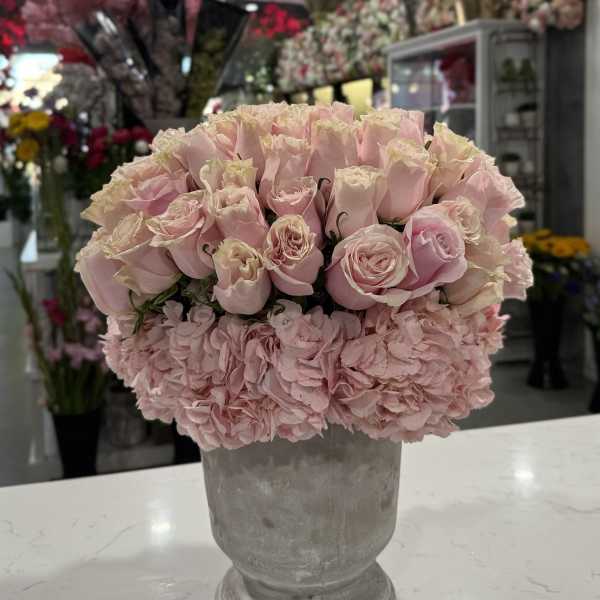Pink roses and hydrangeas arranged in a gray pedestal vase