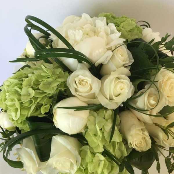 Bouquet of white roses and green hydrangeas with dark ribbon loops