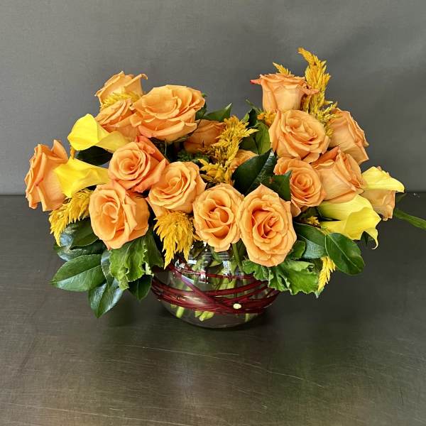 Orange roses and yellow calla lilies in a glass bowl vase