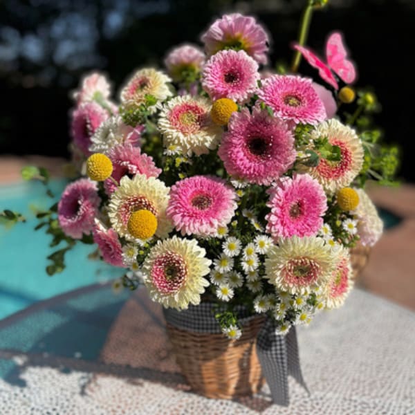 Basket of pink and cream daisy-like flowers with yellow accents