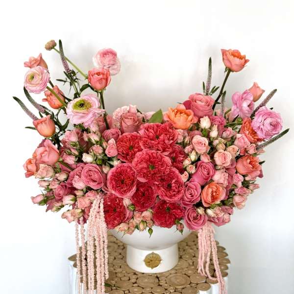 Large pink and coral floral arrangement in a white vase