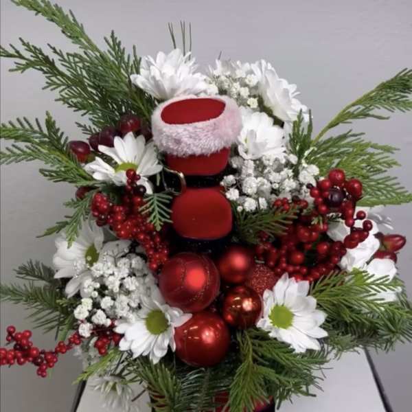 Christmas arrangement with white daisies, red ornaments, and evergreen branches