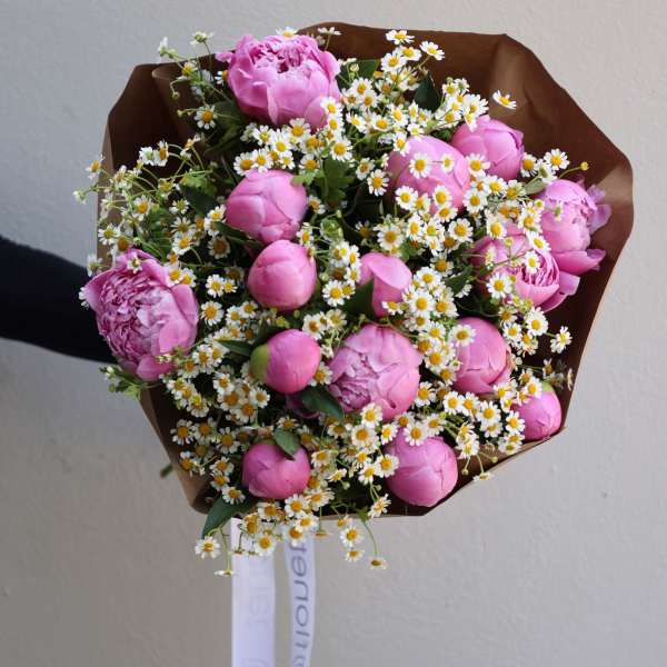 Pink peonies and tiny white daisies in brown paper wrap