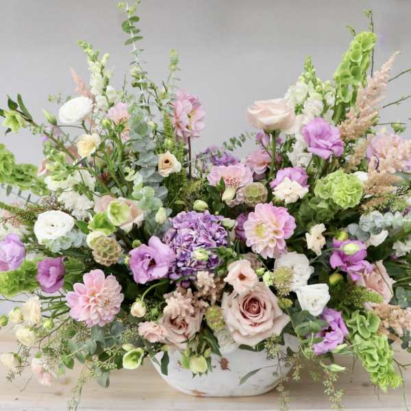 Large pastel floral arrangement in a white bowl vase