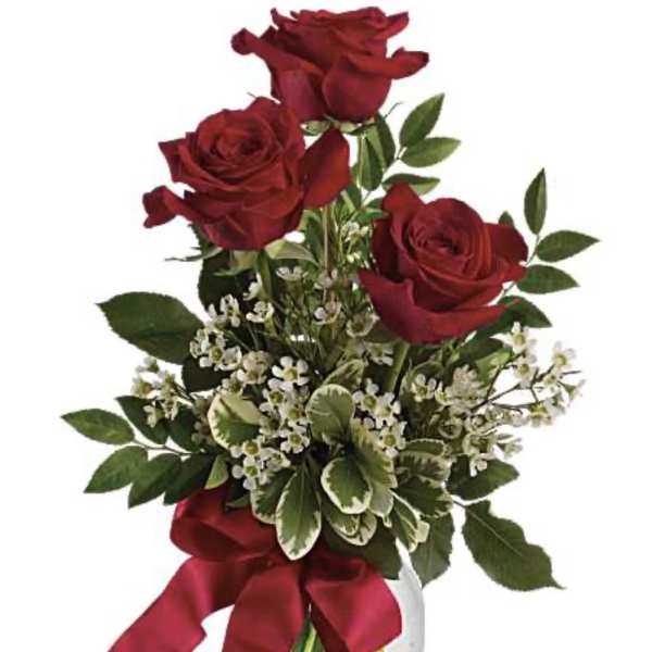 Red roses in a clear glass vase with a burgundy ribbon