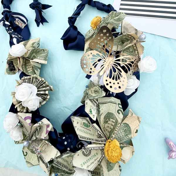 Money lei with ribbon and paper flowers beside a graduation card
