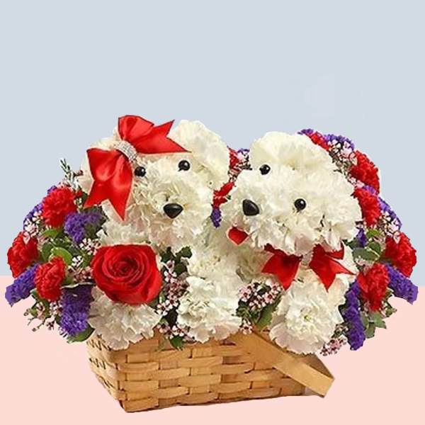 Two white teddy bears in a flower basket with red bows and roses