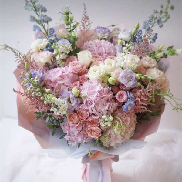 Large pastel bouquet of pink, white, and lavender flowers wrapped in pink paper