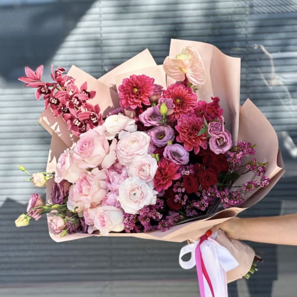 Pink and purple mixed bouquet wrapped in blush paper with ribbon