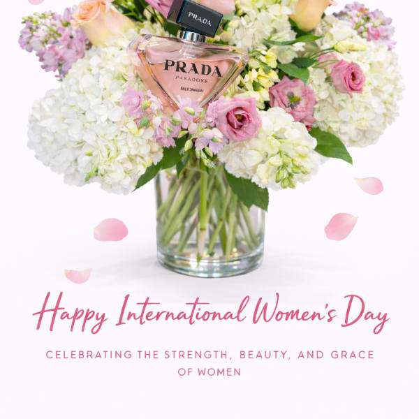 Pink and white flower arrangement in a glass vase with a Prada perfume bottle