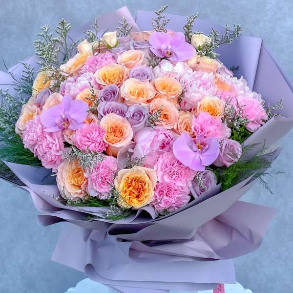 Lavender-wrapped bouquet of pink and peach roses with purple orchids
