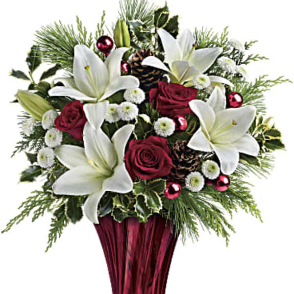 White lilies and red roses in a red glass vase with holiday accents
