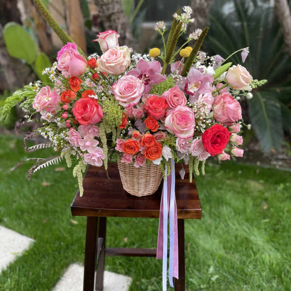 Mixed pink and coral rose arrangement in a wicker basket