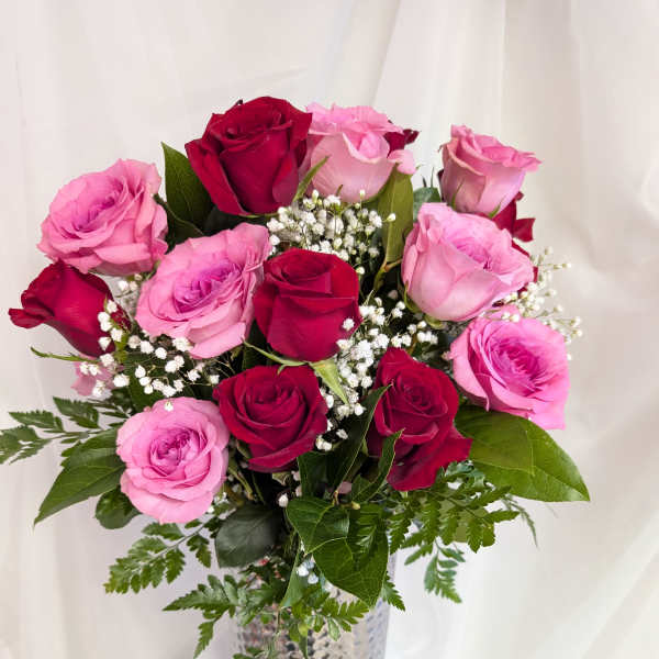 Tall arrangement of red and pink roses with baby's breath in a silver textured vase