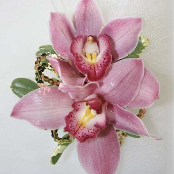 Pink orchid corsage with sequined accents on a white background