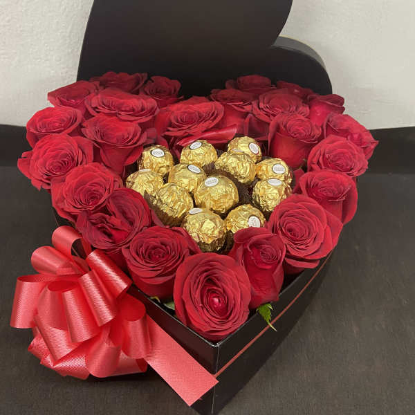 Heart-shaped box of red roses with gold-wrapped chocolates and a red ribbon