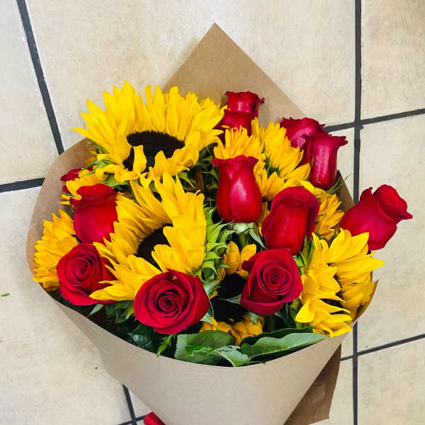 Bouquet of red roses and yellow sunflowers wrapped in brown paper