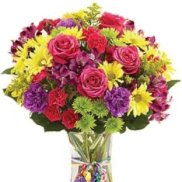 Colorful bouquet of roses, daisies, and carnations in a clear glass vase