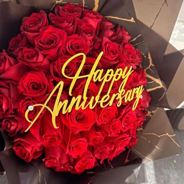 Bouquet of red roses with a gold Happy Anniversary topper