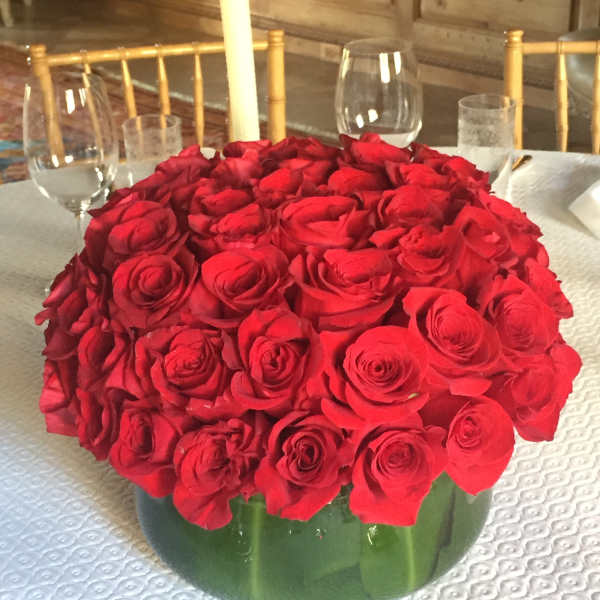 Large bouquet of red roses in a green vase on a table