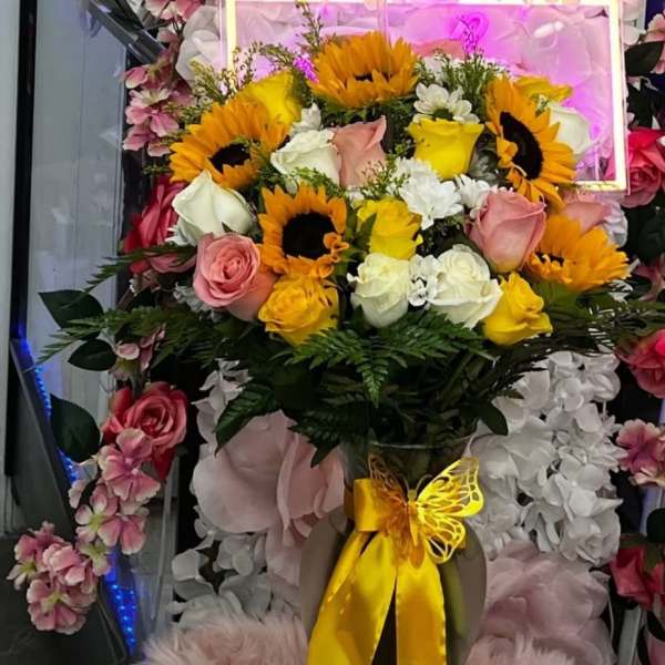 Bouquet of sunflowers and roses with a yellow ribbon in a vase