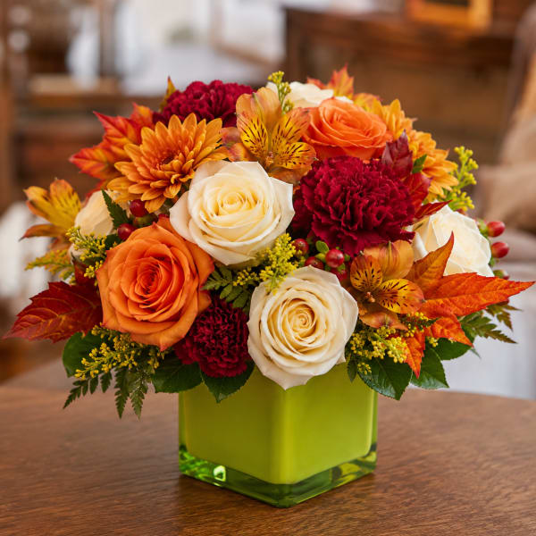 Bouquet of orange and white roses with red carnations in a green vase