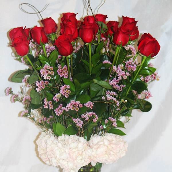 Bouquet of red roses and pale pink flowers in a tall glass vase
