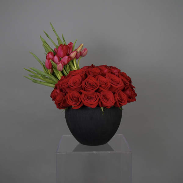 Red roses and pink tulips arranged in a black vase